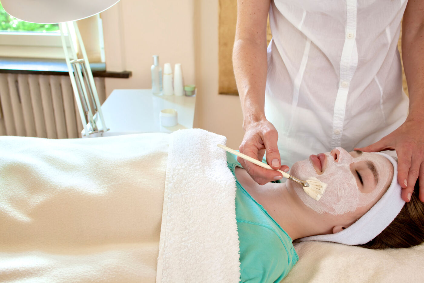 Esthetician brushing a chemical peel onto a client's face